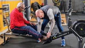 Fitness Trainer helping a client to set themselves up on a piece of fitness equipment at one of the local gyms in Huddersfield